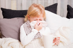 little girl sneezing into tissue