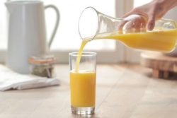 pouring orange juice into a glass on a table