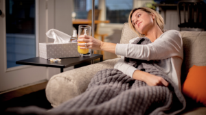 woman on couch sick with cup of orange juice