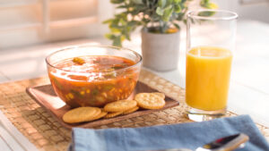 bowl of soup with crackers and a glass of orange juice