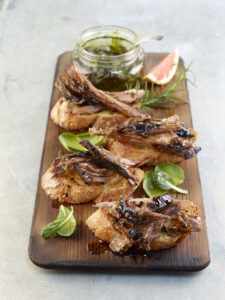 Smoked lamb with sauce on a wood cutting board.