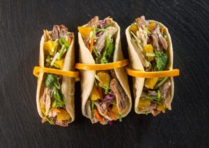 Three Tacos filled with pork, greens and orange twist