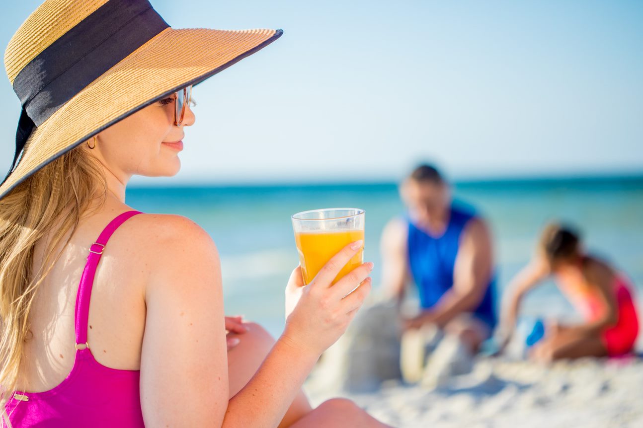 woman drinking orange juice on the beach