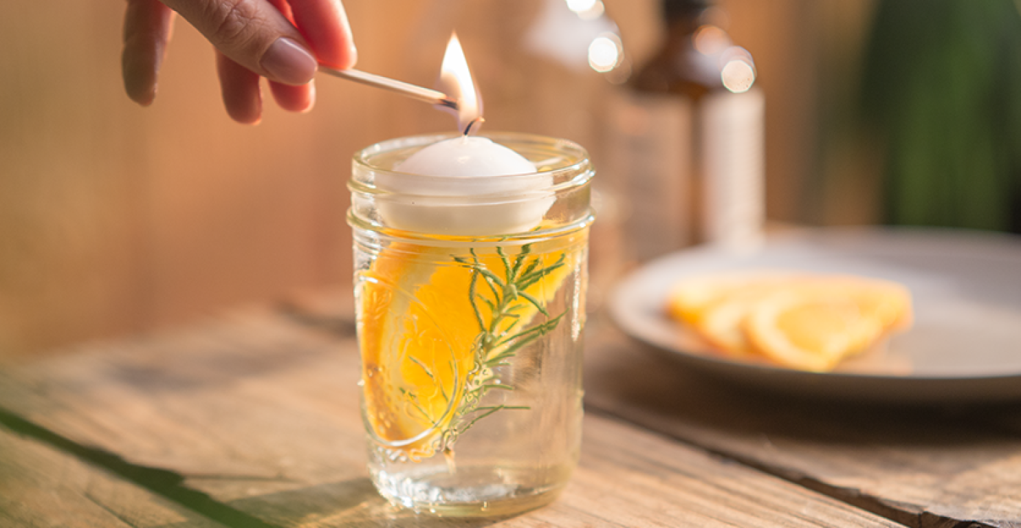 floating candle in a glass above an orange slice