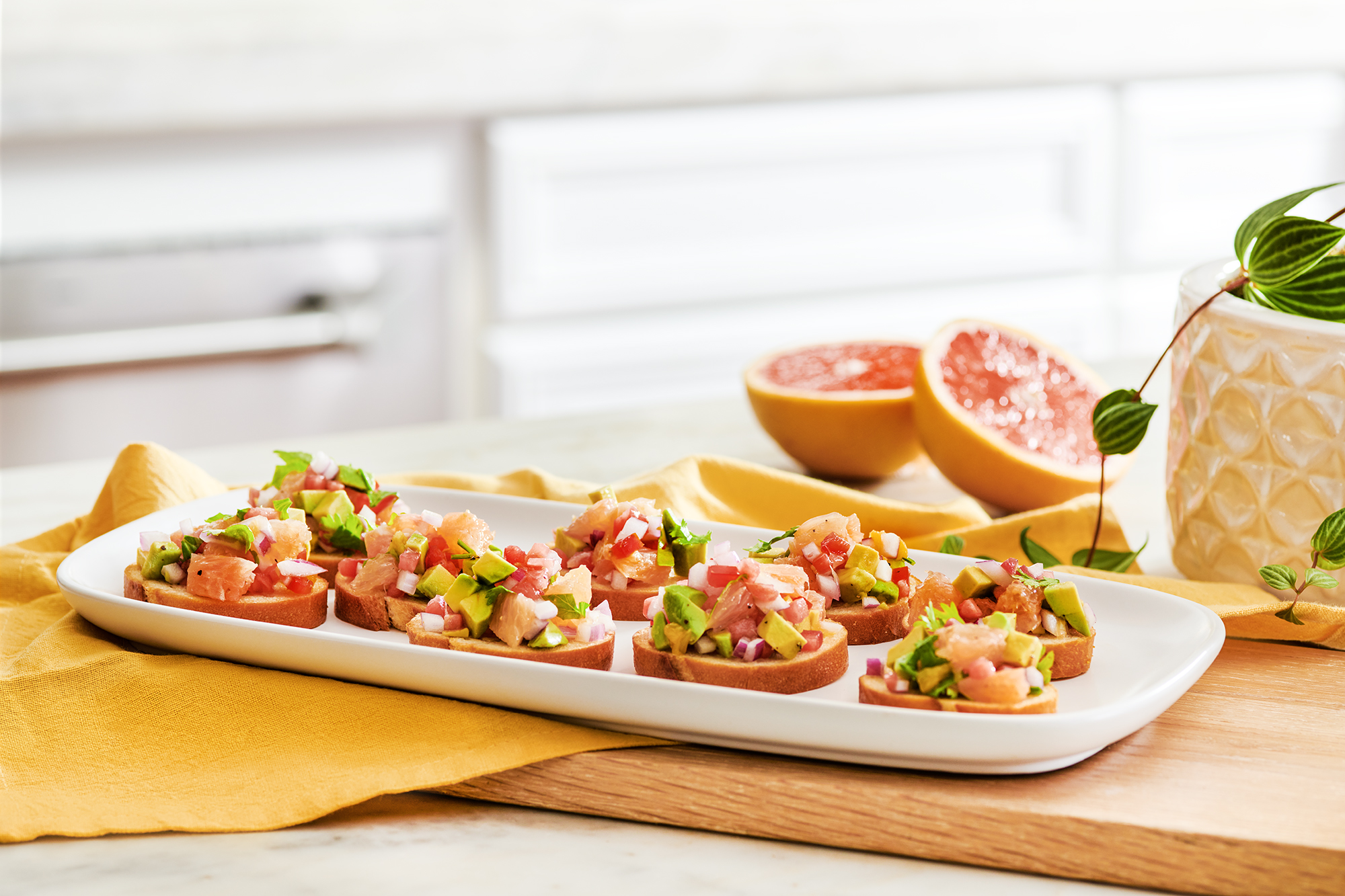 A white oval plate with grapefruit avocado bruschetta