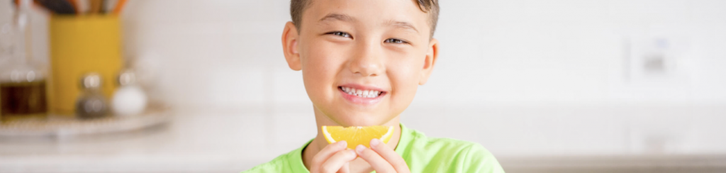 Photo of a child smiling with an orange slice